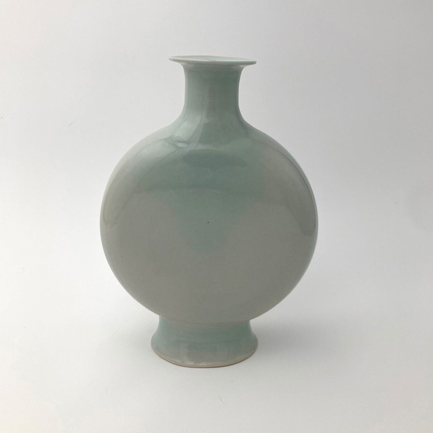 Green ceramic canteen shaped vase on a white background