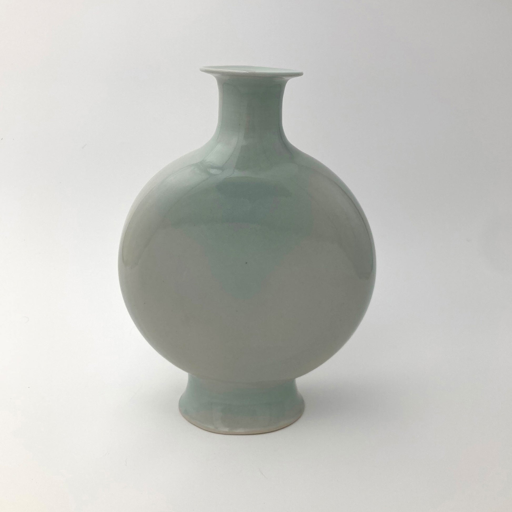 Green ceramic canteen shaped vase on a white background