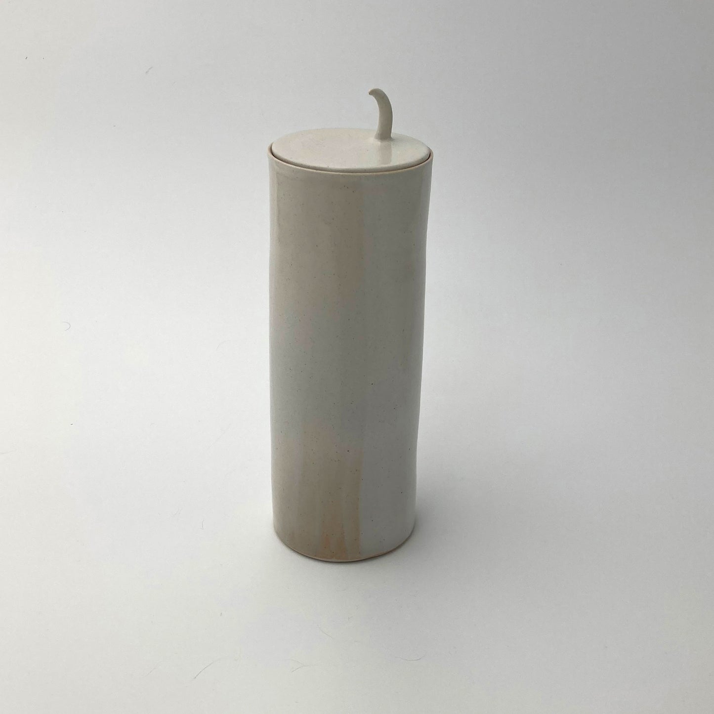 Cylindrical ceramic ginger jar with lid and pull handle on a white background
