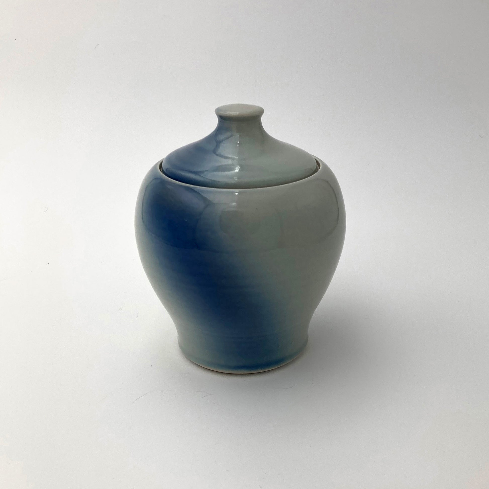 Ceramic jar with a gradient blue to gray finish on a white background