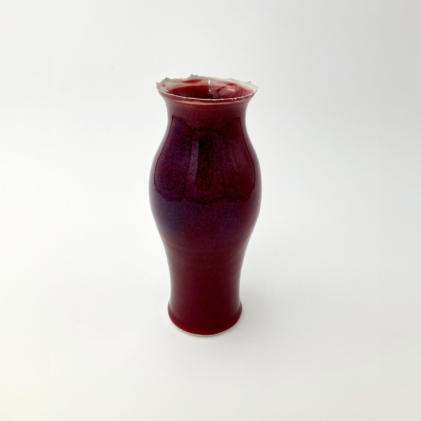 Deep red ceramic vase purple undertones on a white background