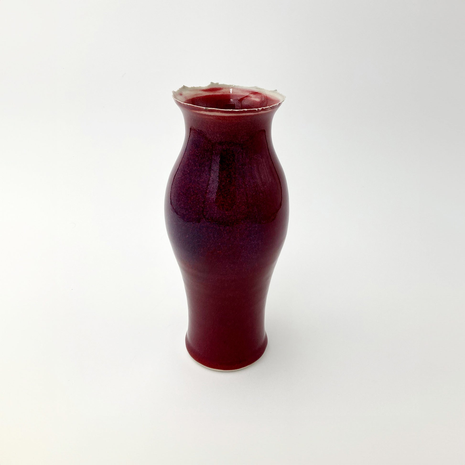 Deep red ceramic vase purple undertones on a white background